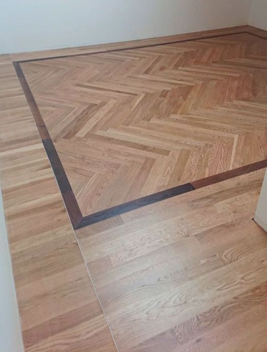 Instalación de tarima tradicional maciza de roble con diseño en espiga y bordes enmarcados, barnizada al agua