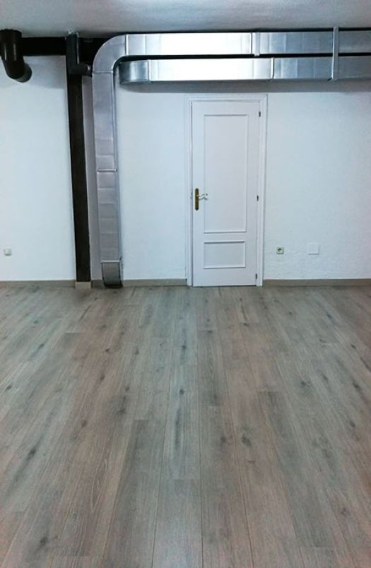 Local comercial recién pintado y con instalación de parquet laminado de acabado gris claro