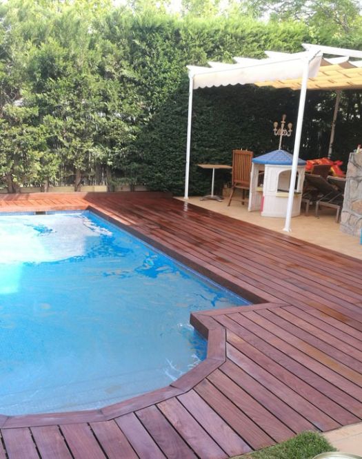 Tarima de madera para exterior recién instalada alrededor de una piscina.